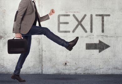 Male academic walking in direction of exit sign