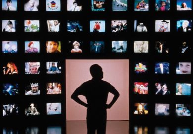 Male silhouette facing wall of television screens