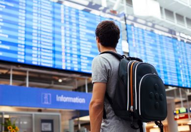 Male student looking at airport departures board