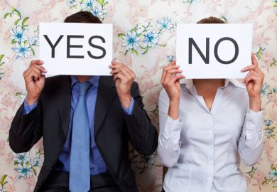 Man and woman holding yes/no cards in front of faces