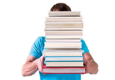 Man carrying pile of books with face hidden