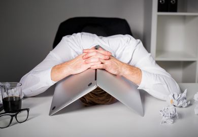 Man hiding under laptop
