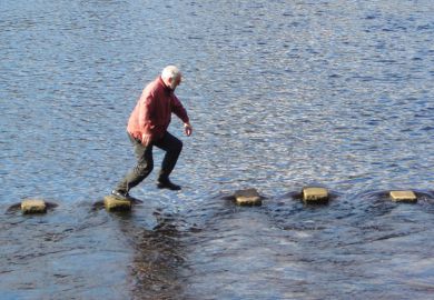 Man leaping across stepping stones in sea inlet Man leaping across stepping stones in sea inlet