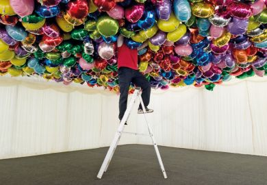 Man on ladder with head in balloons