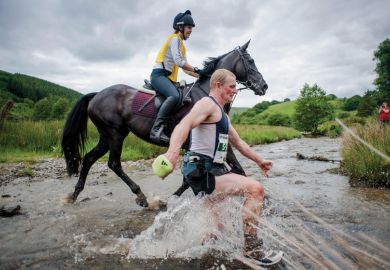 Man racing horse across shallow river