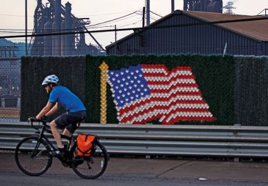 Man riding bicycle past United States of America flag Man riding bicycle past United States of America flag