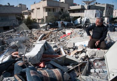 Man sits in rubble of Palestinian National Authority Council of Ministers building