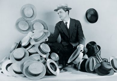 Man sitting on floor surrounded by boater hats