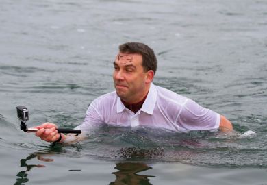 Man standing in water taking selfie photograph