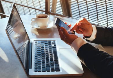 Man using Apple iPhone smartphone and MacBook laptop