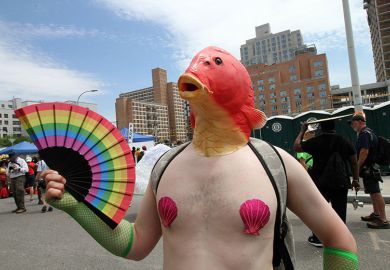 A man wearing a fish mask and holding a rainbow fan during the Mermaid Parade in Brooklyn. To illustrate that academia must ‘engage with’ anti-woke research critics such as Charlotte Gill, who criticised research on ‘queer fish’.