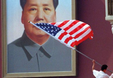 A worker installs an American flag in front of the portrait of China's late Chairman, Mao Zedong, which hangs on Tiananmen Gate in the centre of Beijing