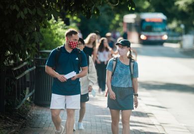 Masked students walk along Hillsborough Street on the North Carolina State University campus early Wednesday evening, August 18, 2021.