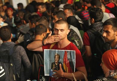 A migrant from Syria holds a picture of Angela Merkel