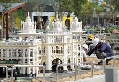 Construction workers work near a miniature of Kuala Lumpur's railway station. To illustrate how universities in Asia are responding to the fast growth of cities.