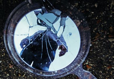 Reflection of man in cracked mirror