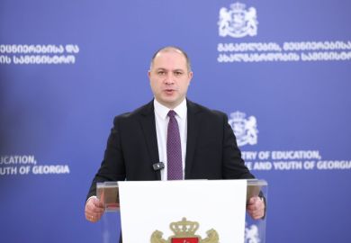 Georgia's education minister speaking at a lecturn in front of a blue backround