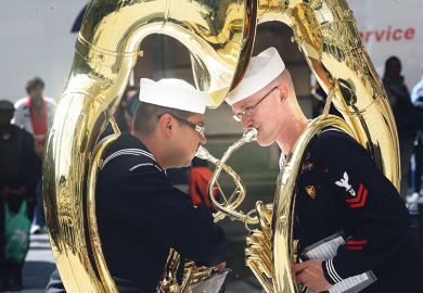 two military sousaphone players as metaphor for two sides uniting 