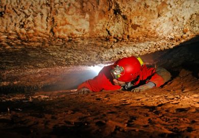 Man crawling through a narrow cave