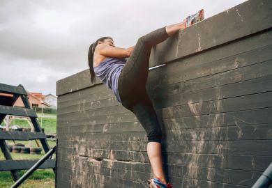 A woman climbing over a fence on an obstacle course