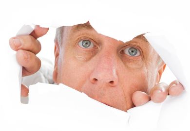 Man peeks through tear in paper