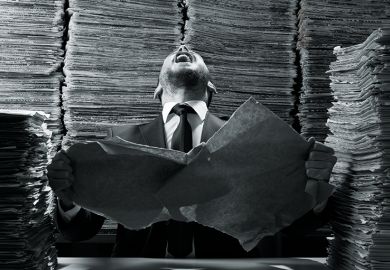 A man laughing amid a pile of paperwork