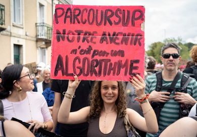 A high school student holds a red placard reading PARCOURSUP OUR FUTURE IS NOT AN ALGORITHM during a high school and university student demonstration in France
