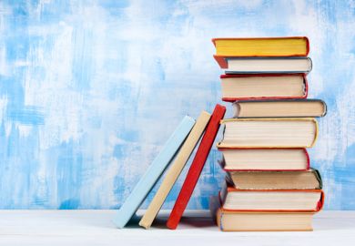 A stack of book beside a blue wall A stack of book beside a blue wall