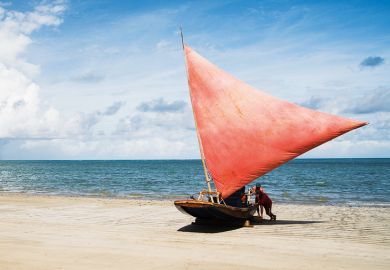 People pushing sailboat from sea onto beach