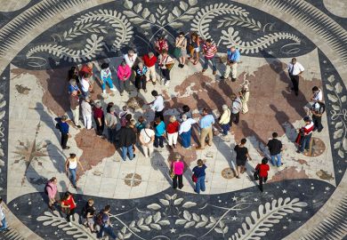 Tourists examining map of the world and compass rose on pavement behind Monument to the Discoveries, Lisbon, Portugal. To illustrate the Academy of Management (AOM) holding conferences outside the US.