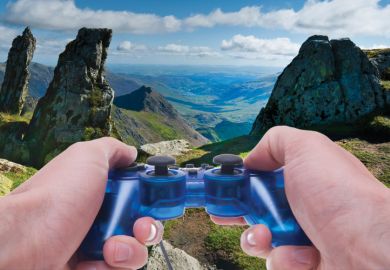 Person holding Sony PlayStation controller in hills