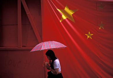 A large banner Chinese flag hangs over a pedestrian under an umbrella. To illustrate that there is ‘little universities can do’ to stop Beijing interference. A large banner Chinese flag hangs over a pedestrian under an umbrella. To illustrate that there is ‘little universities can do’ to stop Beijing interference.