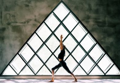 woman doing yoga by large triangular window