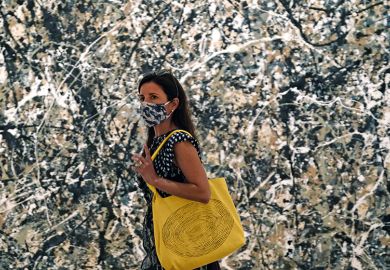 Woman in mask walking past a Pollock painting