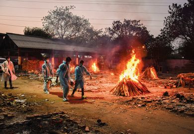 Workers carry the body of a person who has died of Covid-19 as funeral pyres burn during a mass cremation at a crematorium, New Delhi, 2021/05/03  