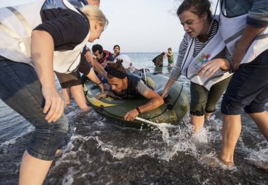 Kos, Greece - October 2015: Volunteers give a hand to migrants from Afghanistan who arrived at Kos from Turkey on a dinghy