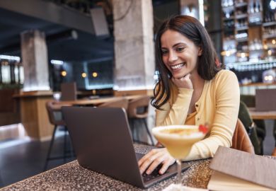 A woman drinks a cocktail and works on her laptop, symbolising residential courses