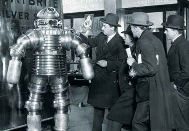 Men examining 1950s-style robot Men examining 1950s-style robot