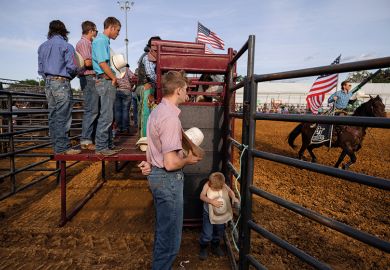  A boy listens to the playing of the national anthem with a group of rodeo participants before the rodeo, USA. To illustrate how university networks in rural areas could bridge social divides.
