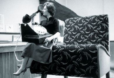 Seated woman using huge telephone