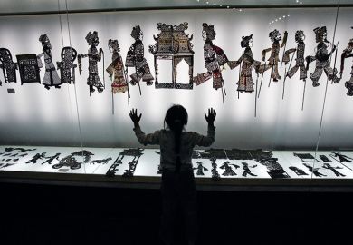 A visitor admires shadow puppets made of leather during an exhibition. China