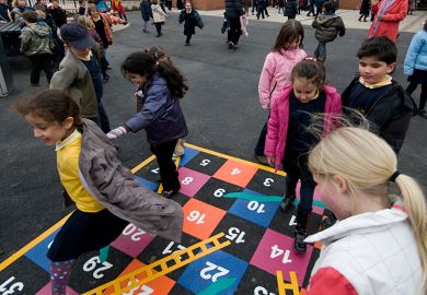 Children playing snakes and ladders in a school playground. To illustrate that the channelling of government funding into charity at the expense of universities has yet to be proven.