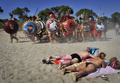 Sunbathers watch Italian re-enactors dressed as Greek hoplites perform the 490 BC battle of Marathon