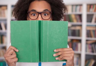 Student peeking behind book, Student Experience Survey 2016 university reviews Student peeking behind book, Student Experience Survey 2016 university reviews