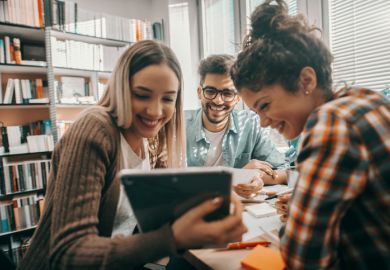 A group of students look at a tablet