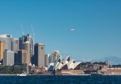 A plane flies over Sydney Opera House