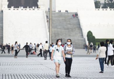 Taipei, Taiwan, March 2, 2020. Two Taiwanese girls, wearing a face mask to protect themselves from the novel coronavirus are walking in the Liberty Square, Taipei, Taiwan.