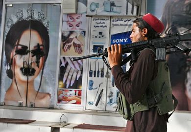 A Taliban fighter walks past a beauty salon with images of women defaced using spray paint in Shar-e-Naw in Kabul, Afghanistan on 18 August 2021.