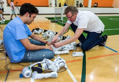 Student and teacher fixing robots, as an illustration of how student support is set to become ‘primary focus’ amid AI rise.