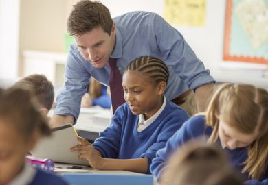 A schoolteacher helps his pupils